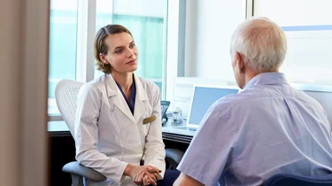 Patient og læge sidder under en konsultation.