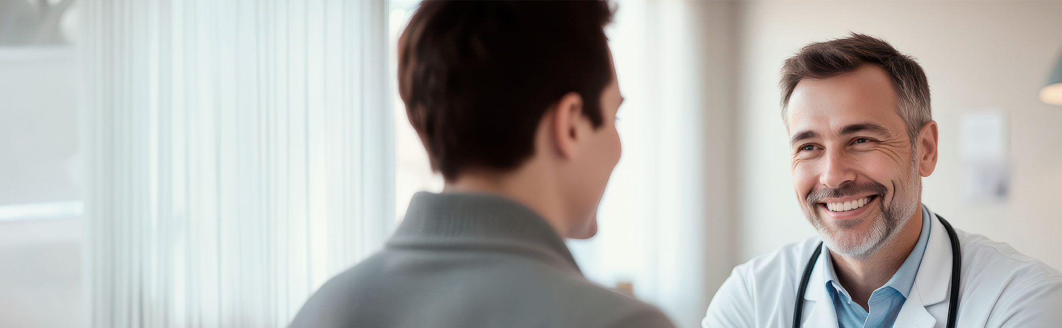 Læge smiler til patient under en konsultation.