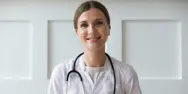 Kvindelig læge smiler ind i kameraet.