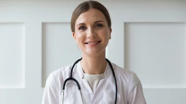Kvindelig læge smiler ind i kameraet.
