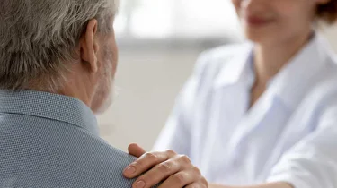 Læge holder på skulderen af en patient,