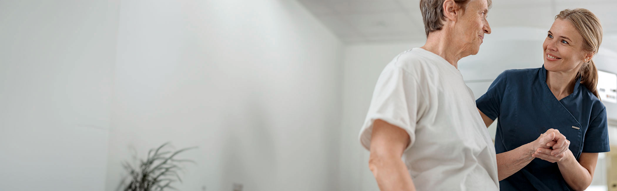 Sygeplejerske holder patient på skulder og smiler.