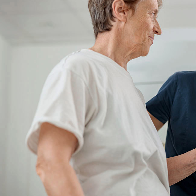 Sygeplejerske holder patient på skulder og smiler.