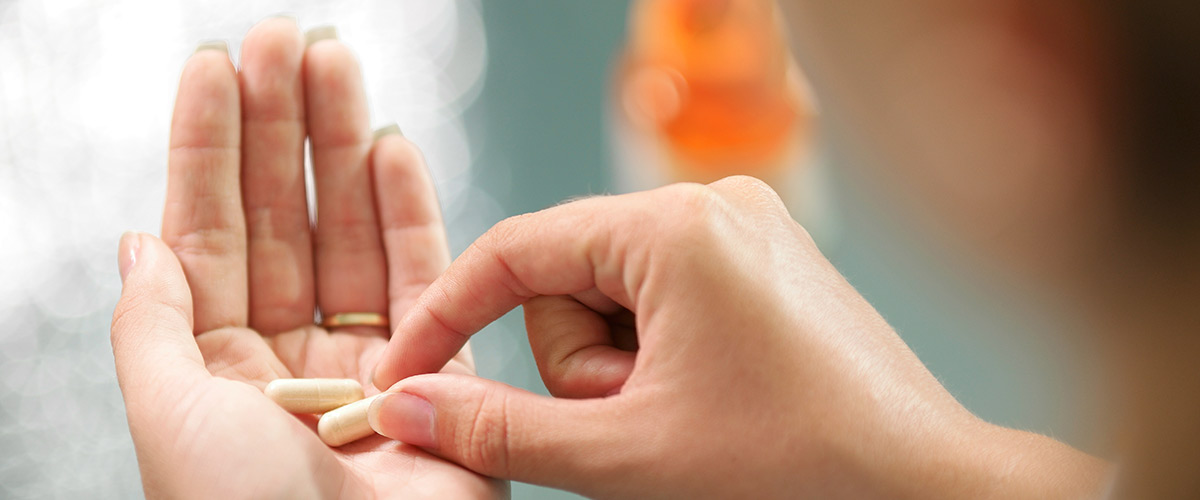 Kvinde skal til at indtage to piller som ligger klar i hendes hånd.