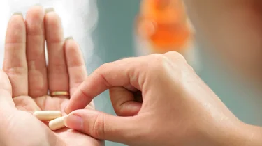 Kvinde skal til at indtage to piller som ligger klar i hendes hånd.