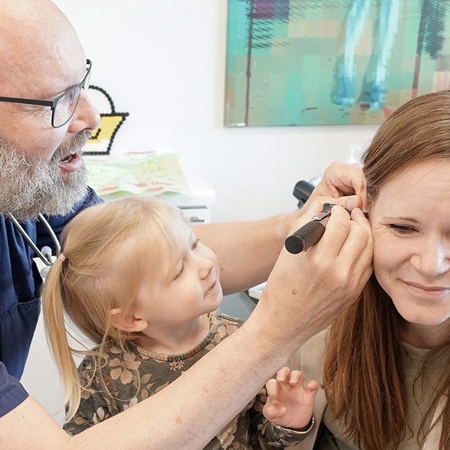 Børnelæge viser barn, hvordan vi kigger i ørerne på barnets mor.