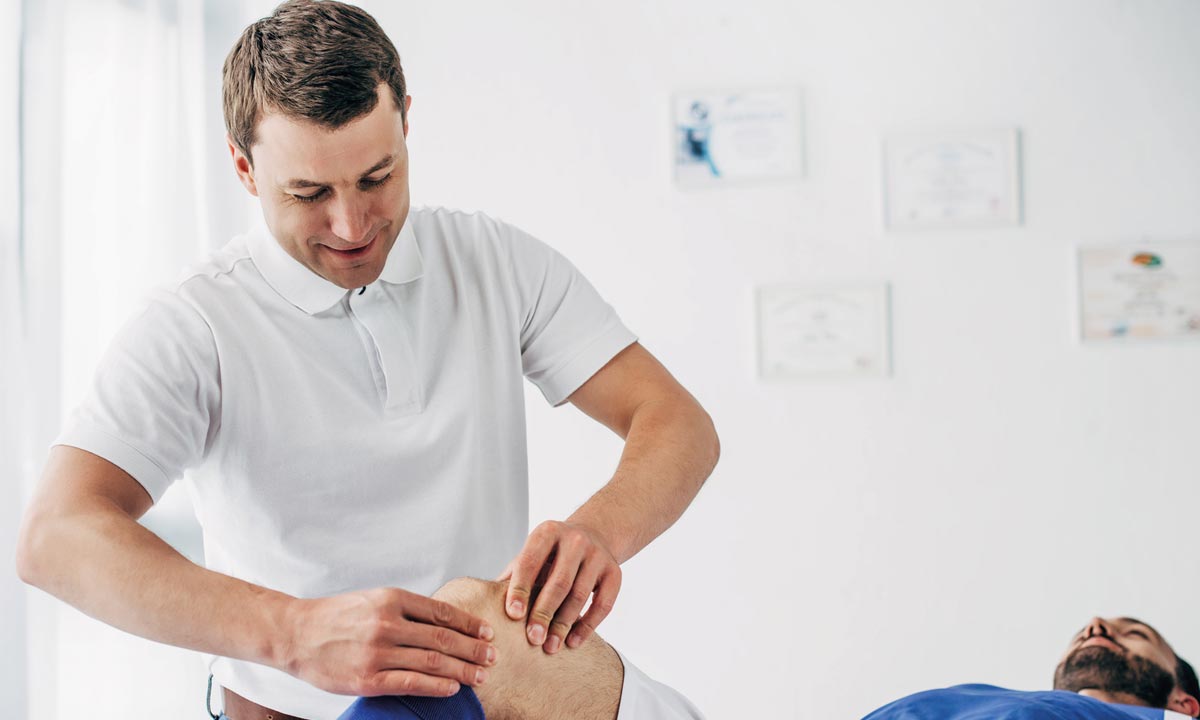 Fysioterapeut masserer patient på knæet.
