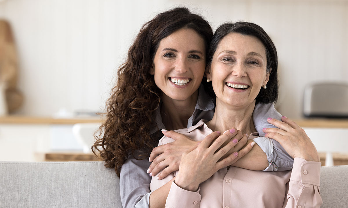Datter holder om mor, og de smiler begge ind i kameraet.