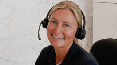 Helbredssygeplejerske i Aleris Health sidder og taler i telefon.