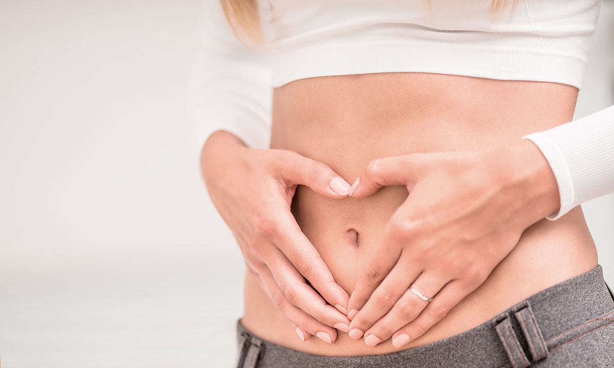 Kvinde danner et hjerte med sine hænder over maven.