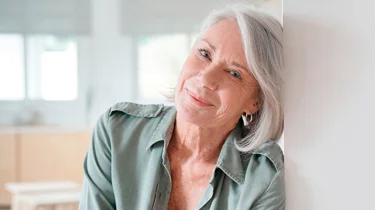 Midaldrende kvinde smiler ind i kameraet.