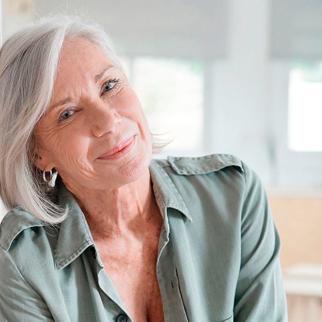 Midaldrende kvinde smiler ind i kameraet.