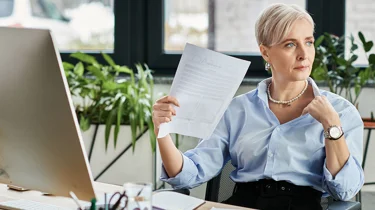 Midaldrende kvinde sidder på et kontor og døjer med hedeture.