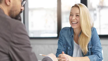 Smilende kvinde sidder til en konsultation hos en erhvervspsykolog.