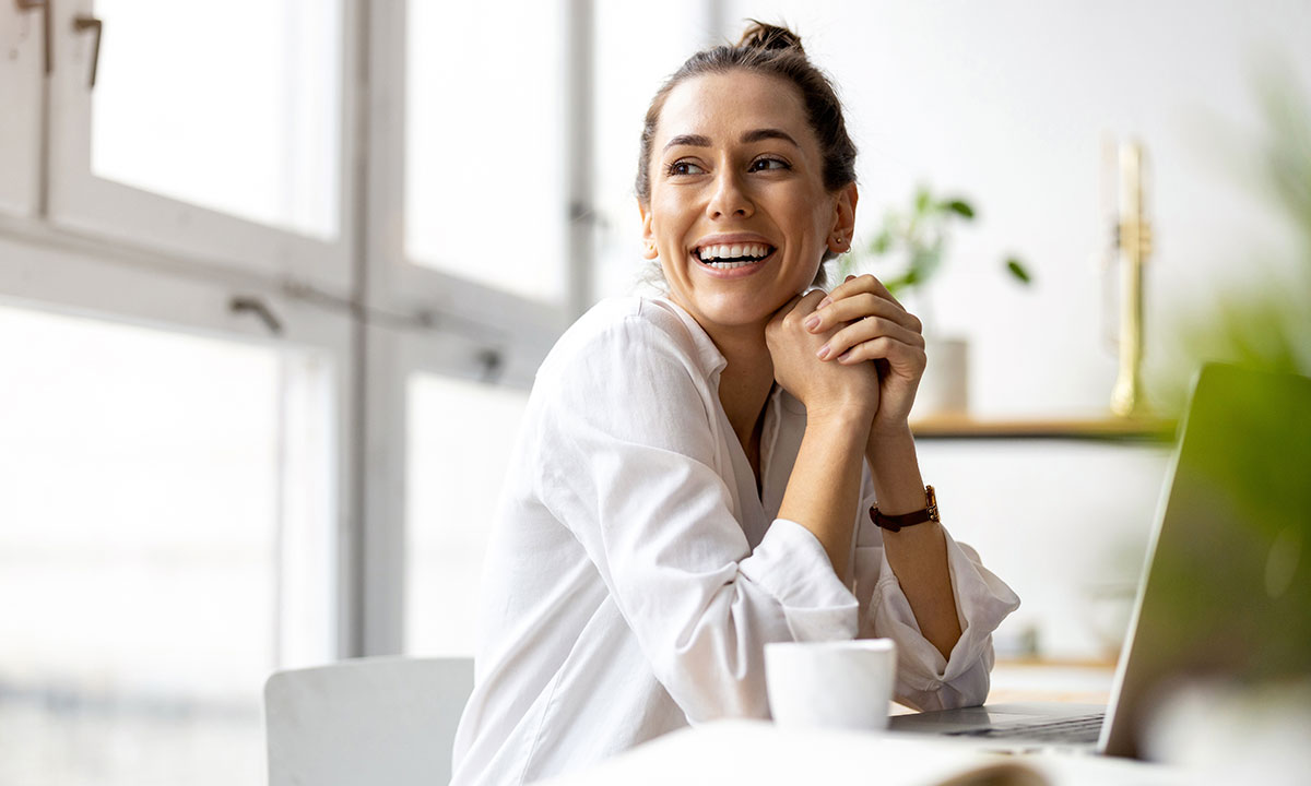 Smilende kvinde ser sig over skulderen og ud af vinduet.