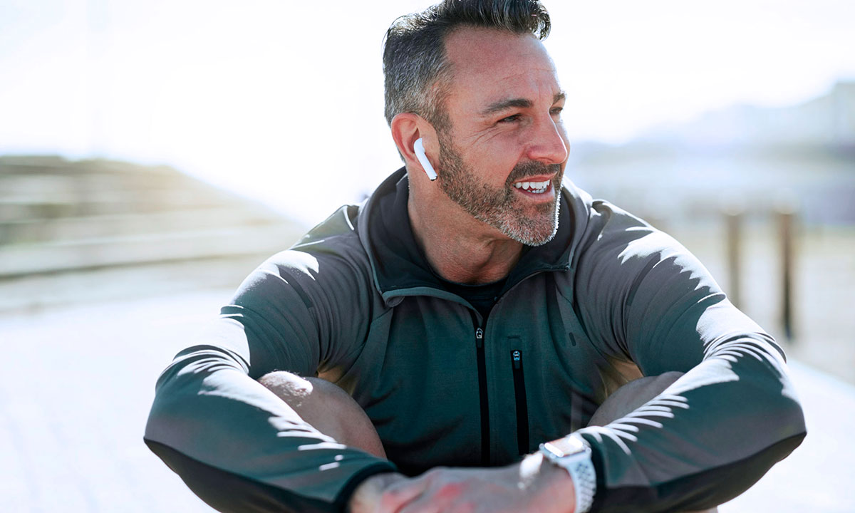 Glad mand sidder i naturen og lytter til musik.