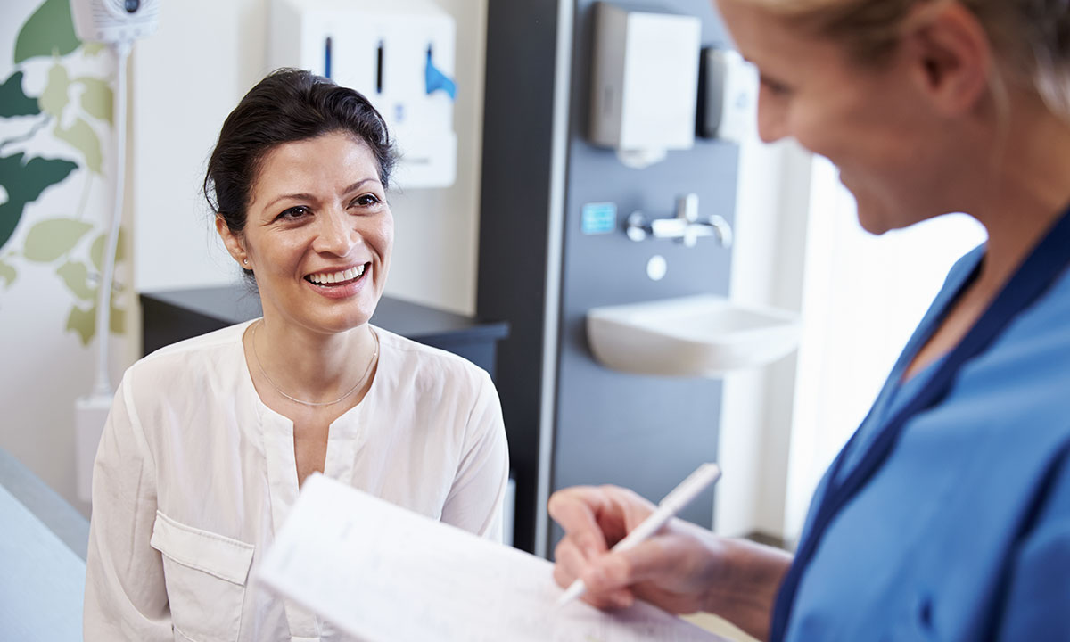 Patient og læge sidder smilende under konsultation.