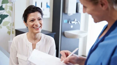 Patient og læge sidder smilende under konsultation.