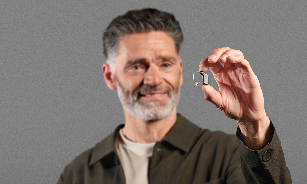 Mand holder lille Oticon RITE høreapparat mellem fingrene