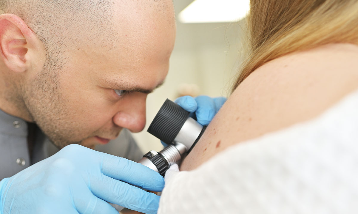 Hudlæge undersøger patients hud med dermatoskop.