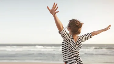 En kvinde laver yoga på stranden ved solnedgang.