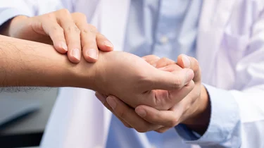 Læge undersøger håndled for karpaltunnelsyndrom.