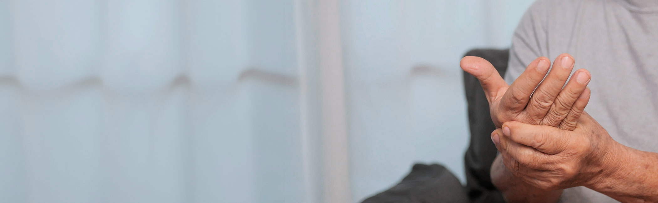 En mand holder om sin hånd på grund af smerter.