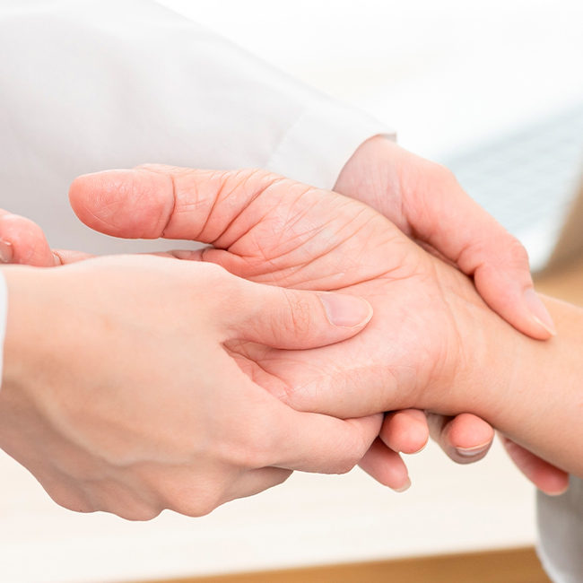 Håndkirurg undersøger en patients hånd.