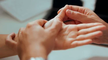 Læge undersøger patient med slidgigt i tommelfingeren.