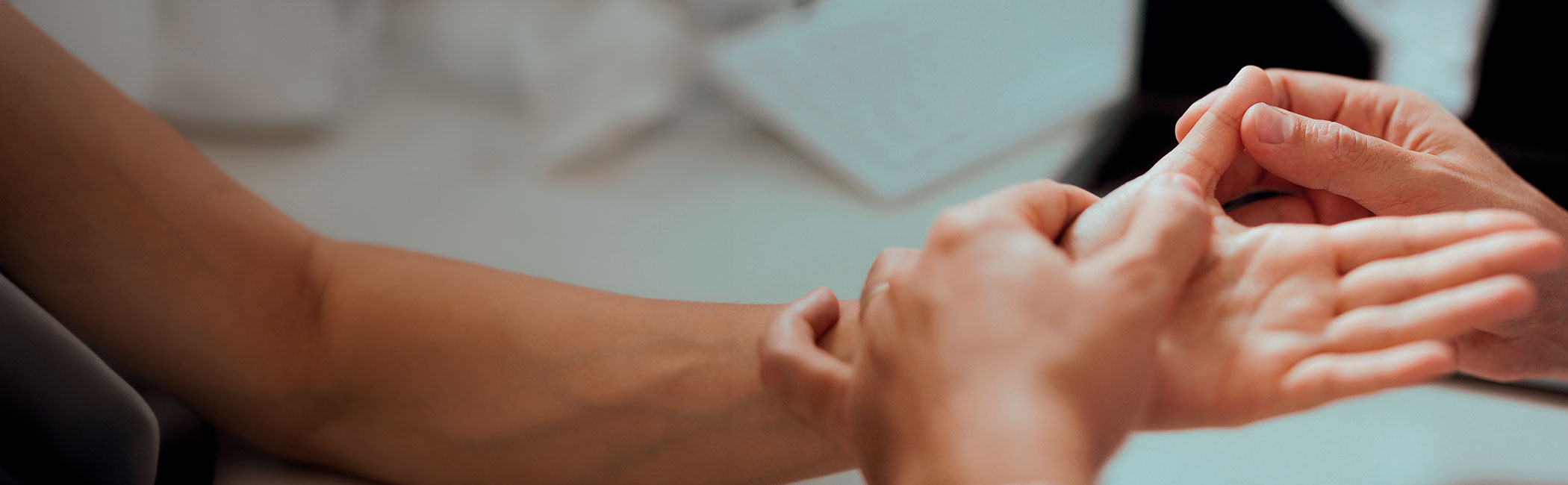 En læge undersøger tommelfingeren på en patient.