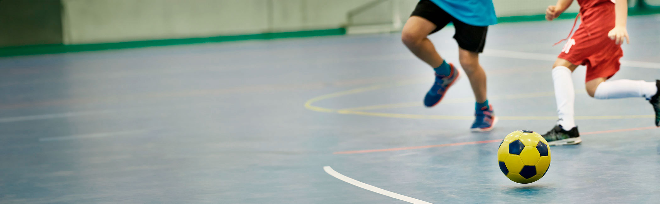 To børn spiller fodbold i en hal.