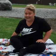 Frederikke på et tæppe i en park smiler til fotografen i perioden før hendes overvægtsoperation