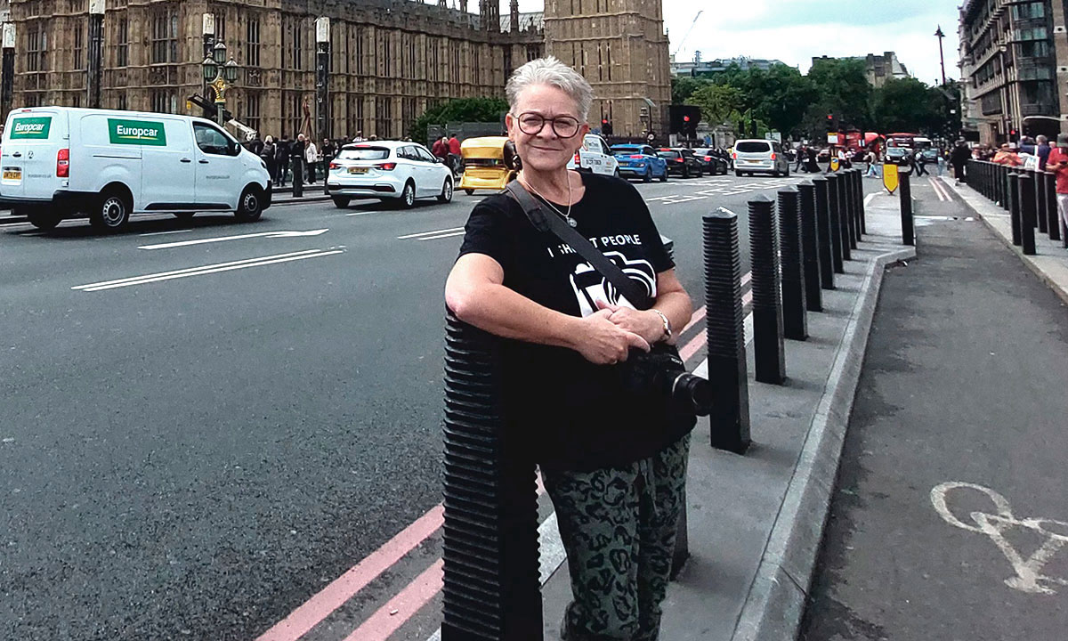 En kvinde står på gaden og smiler.