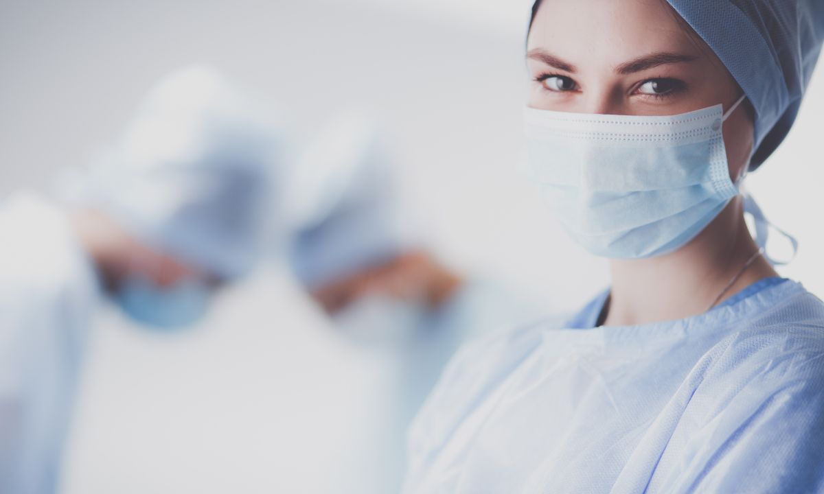 Kvindelig kirurg står i operationstøj.