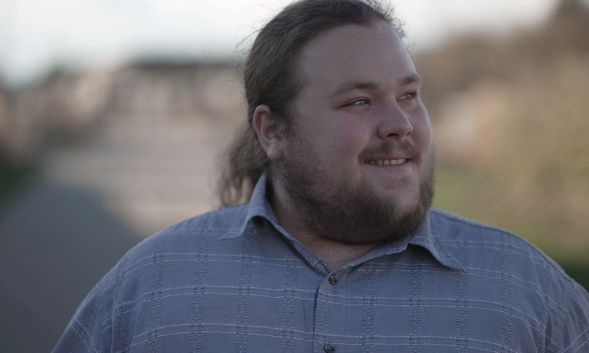 Overvægtig mand går og smiler.