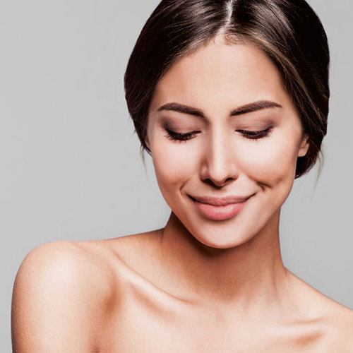 En kvinde kigger smilende ned på jorden.