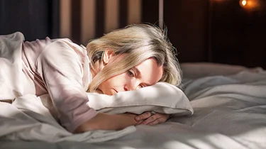 Kvinde 40+ ligger på maven i sengen og kan ikke sove.