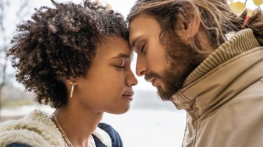 En ung kvinde og mand står med hovederne tæt sammen.